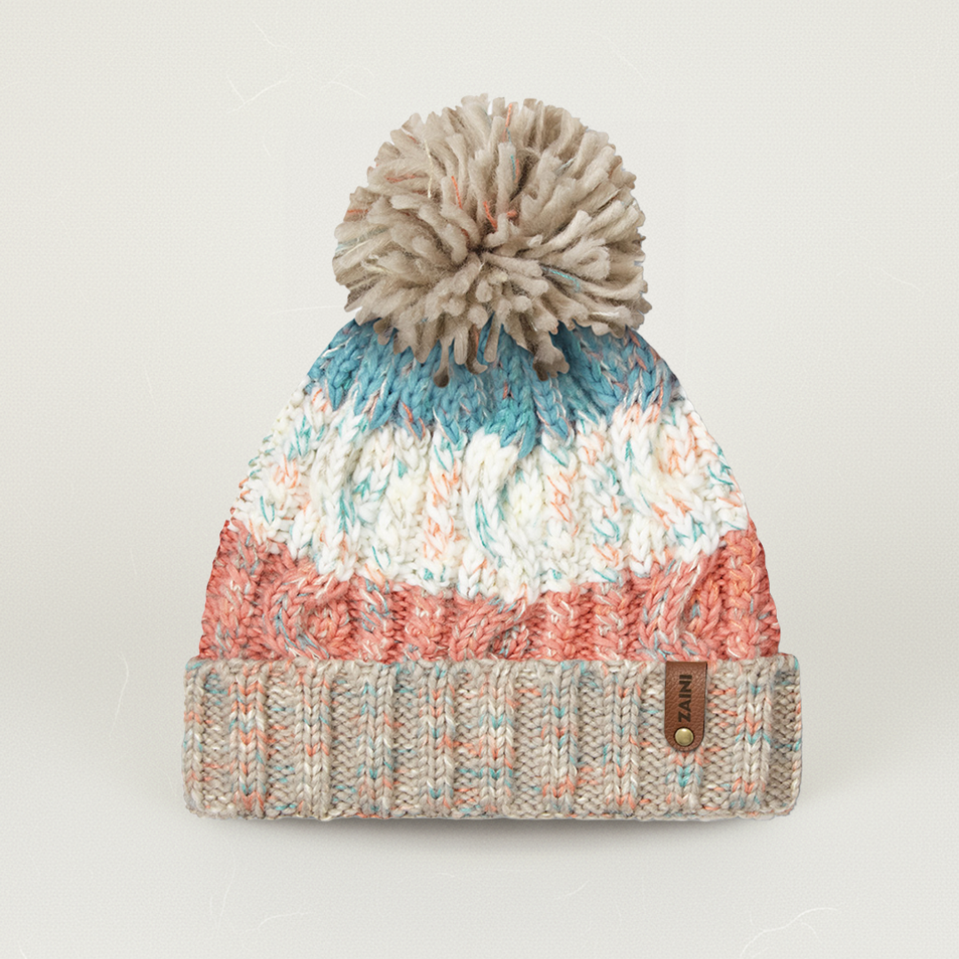 Multicolored knit beanie with a pom-pom on a light gray background
