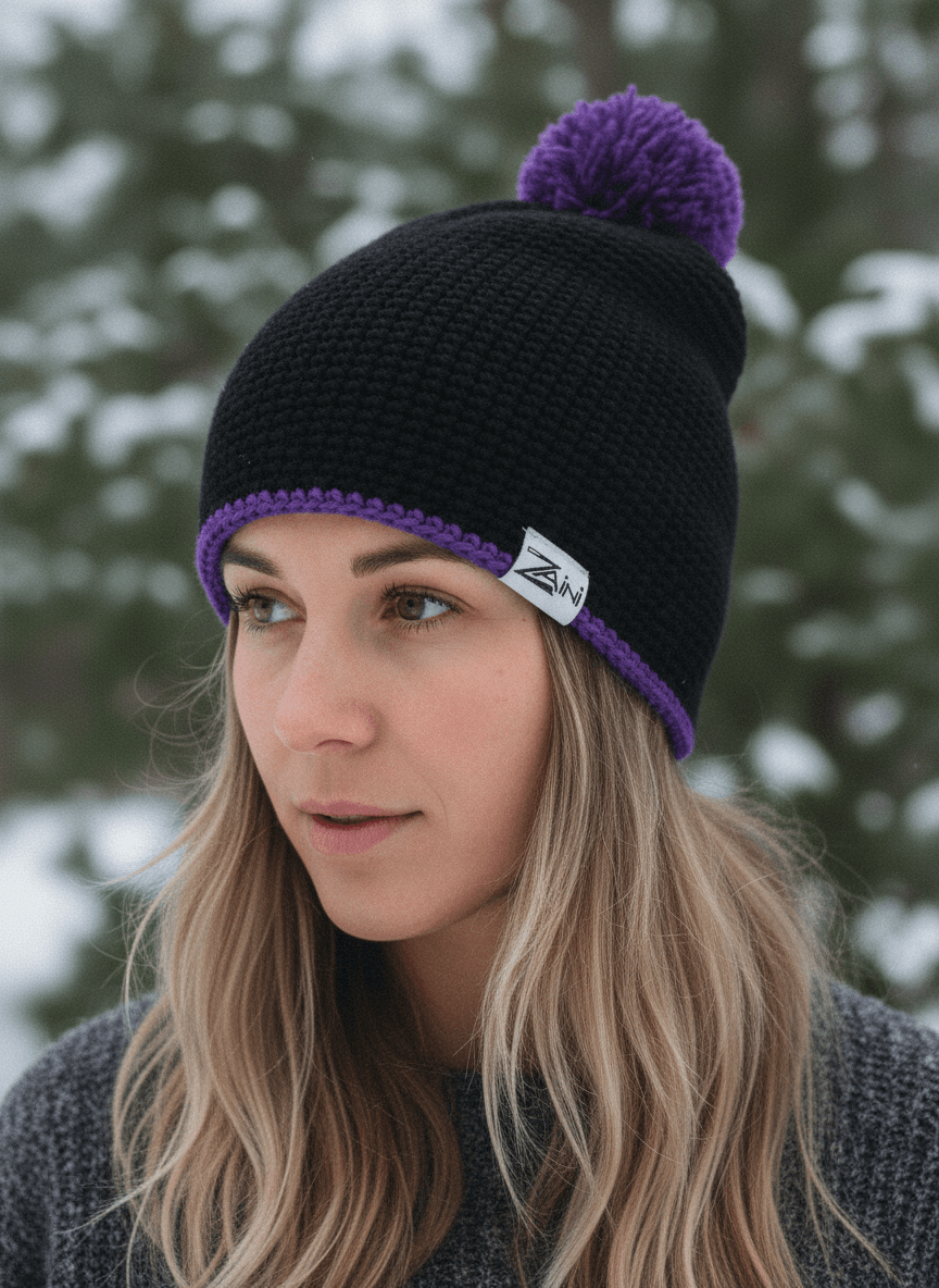 Woman wearing a black knit beanie with a purple pom-pom against a snowy background
