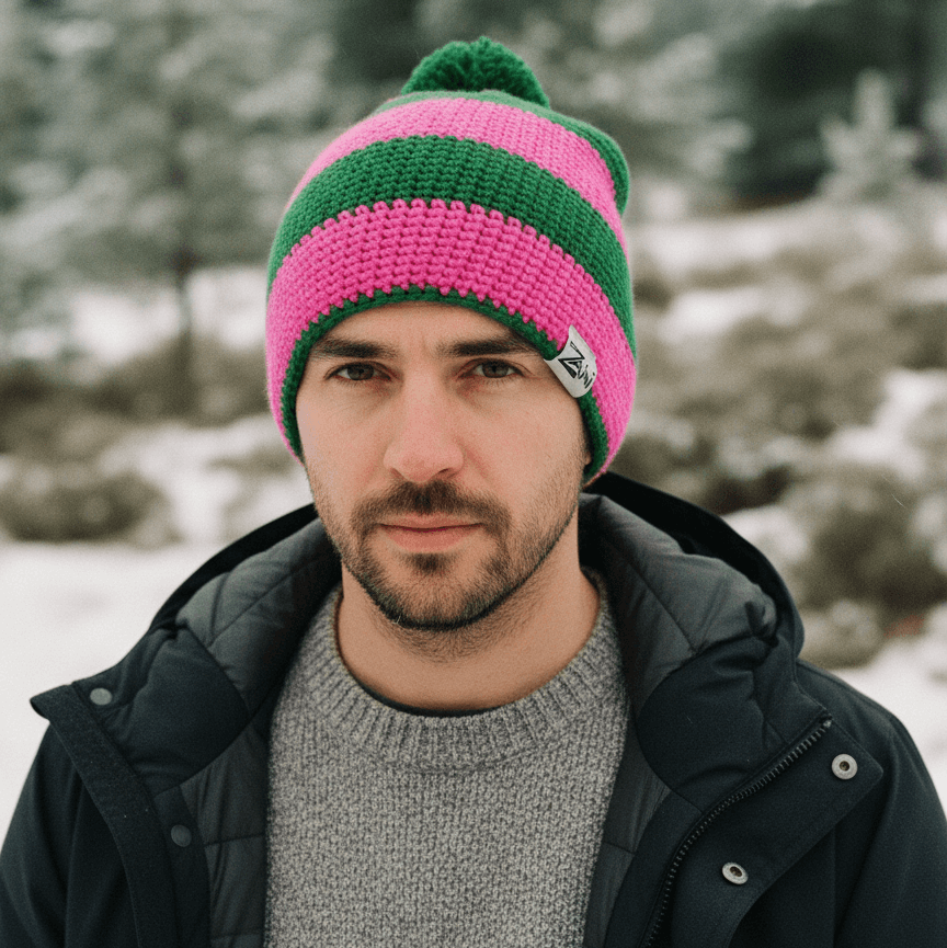 Man wearing a pink and green striped beanie in a snowy forest setting