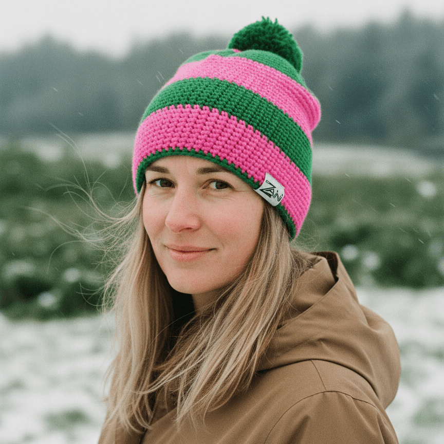 Person wearing a pink and green striped beanie in a snowy landscape