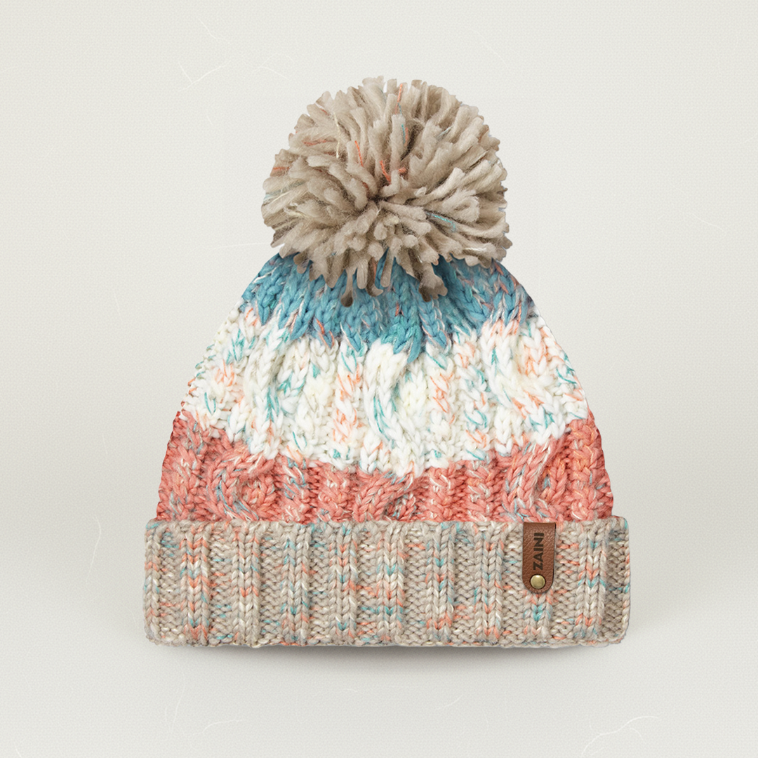 Multicolored knit beanie with a pom-pom on a light gray background