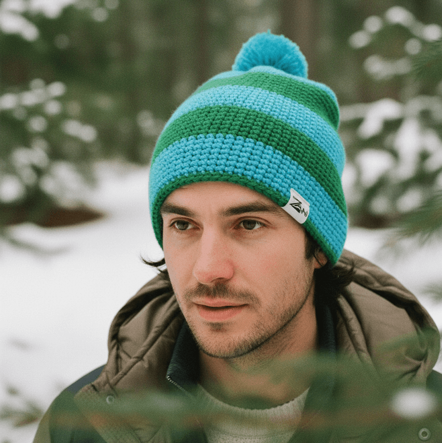 Man wearing a green and blue striped beanie in a snowy forest setting