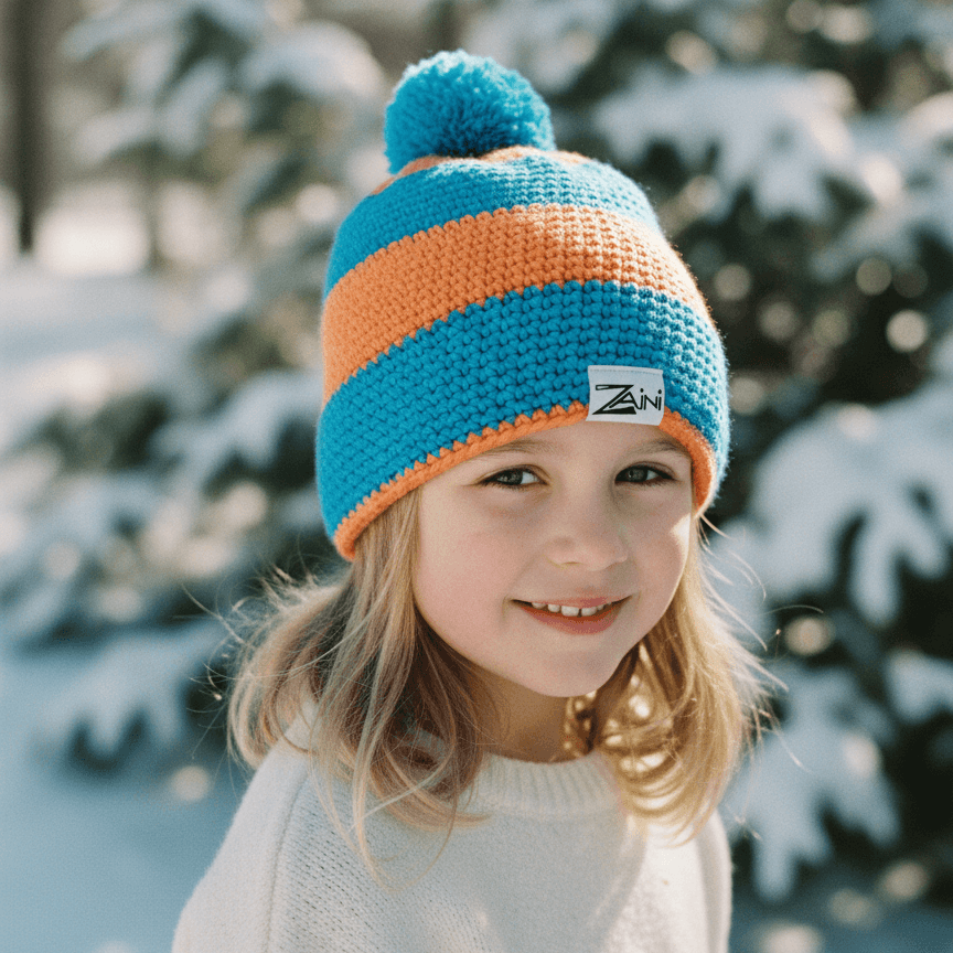 Child wearing a blue and orange striped knit hat with a pom-pom, standing in a snowy forest.