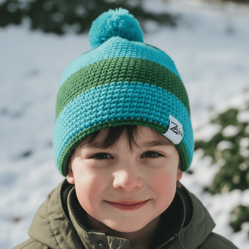 Child wearing a green and blue knit beanie with a pom-pom in a snowy outdoor setting