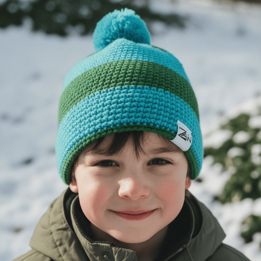 Child wearing a green and blue knit beanie with a pom-pom in a snowy outdoor setting