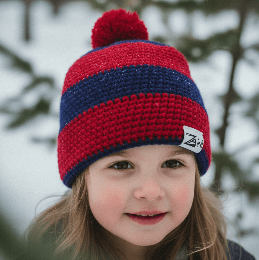 Child wearing a red and blue striped knit hat with a pom-pom in a snowy forest setting