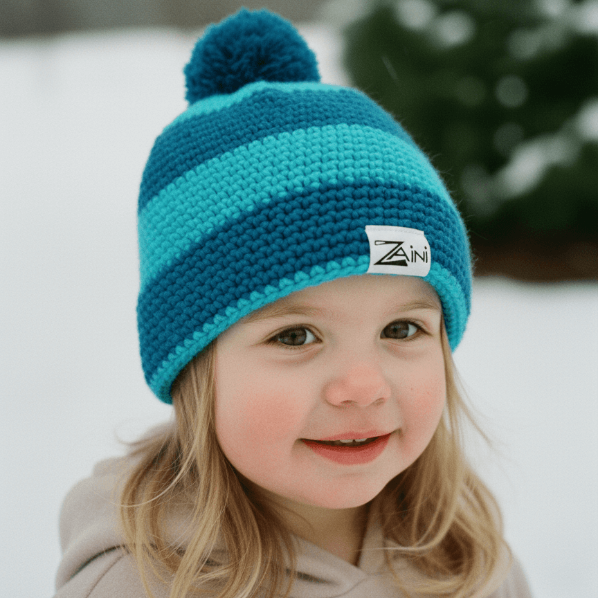 Child wearing a blue knit hat with a pom-pom in a snowy outdoor setting