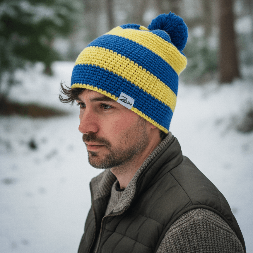 Man wearing a blue and yellow striped knit beanie in a snowy forest setting