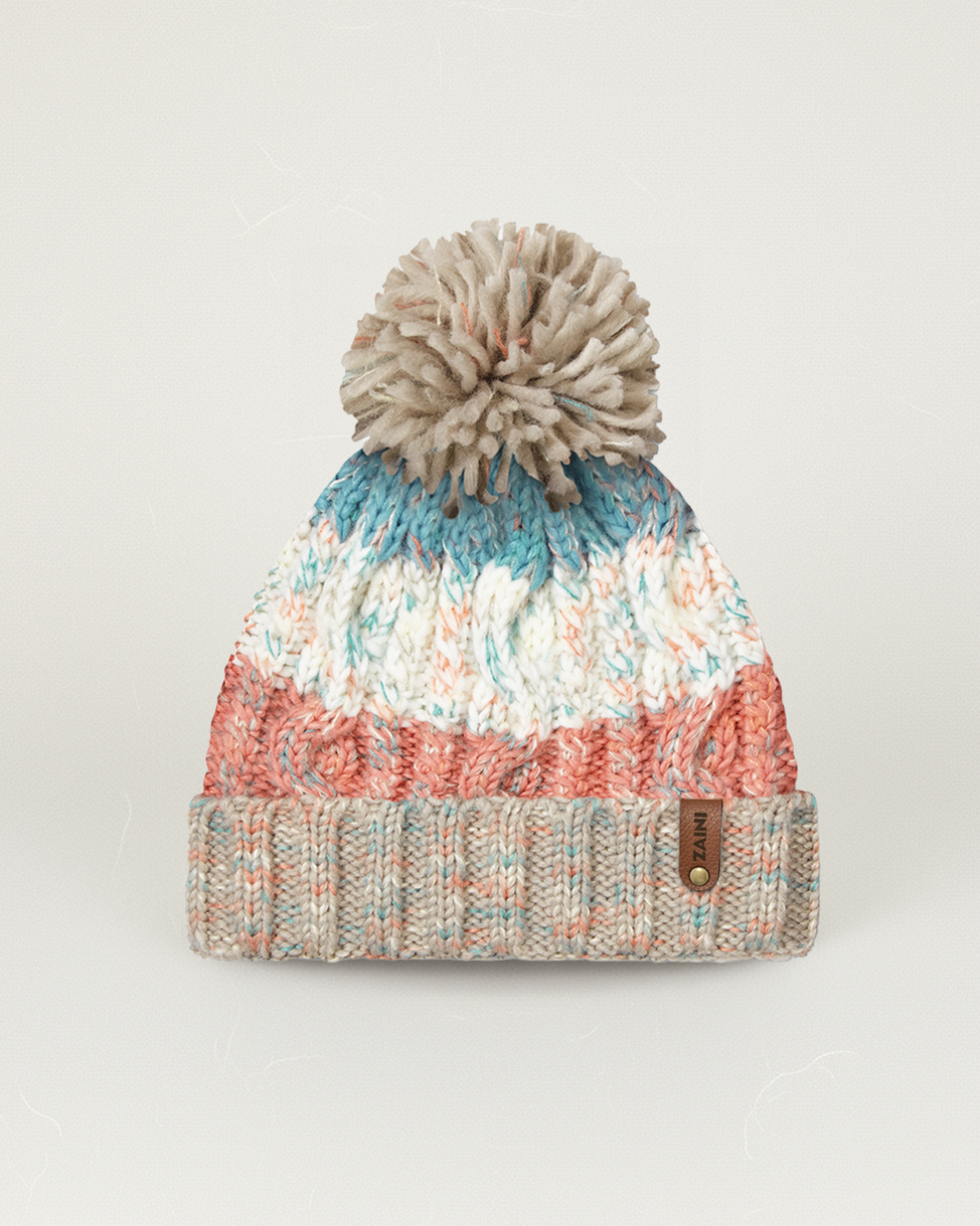 Multicolored knit beanie with a pom-pom on a light gray background