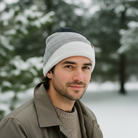 Man wearing a knit beanie and jacket in a snowy landscape