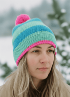 Person wearing a colorful striped beanie with a pom-pom in a snowy landscape