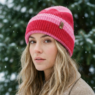 Woman wearing a pink and red striped knit beanie in a snowy forest setting