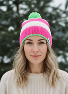Woman wearing a colorful knit beanie with a green pom-pom against a snowy background