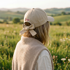 Person wearing a beige cap with a bow in a field