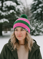 Person wearing a pink and green knit beanie in a snowy landscape