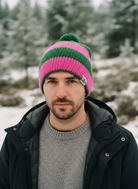 Man wearing a pink and green striped beanie in a snowy forest