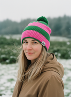 Person wearing a pink and green striped beanie in a snowy landscape