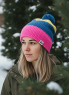 Person wearing a colorful knit beanie with a logo in a snowy outdoor setting