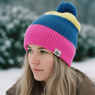Person wearing a colorful knit beanie with a pom-pom in a snowy landscape