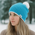 Woman wearing a blue knit beanie with a white pom-pom in a snowy landscape
