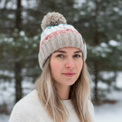 Woman wearing a knitted hat with a pom-pom in a snowy forest