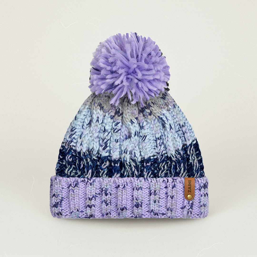 Knitted beanie with a purple pom-pom on a light gray background