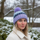 Woman wearing a purple knit beanie with a pom-pom outdoors in winter.