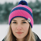 Person wearing a pink and blue knit beanie in a snowy landscape