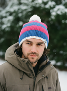 Man wearing a colorful knit beanie and winter coat in a snowy setting