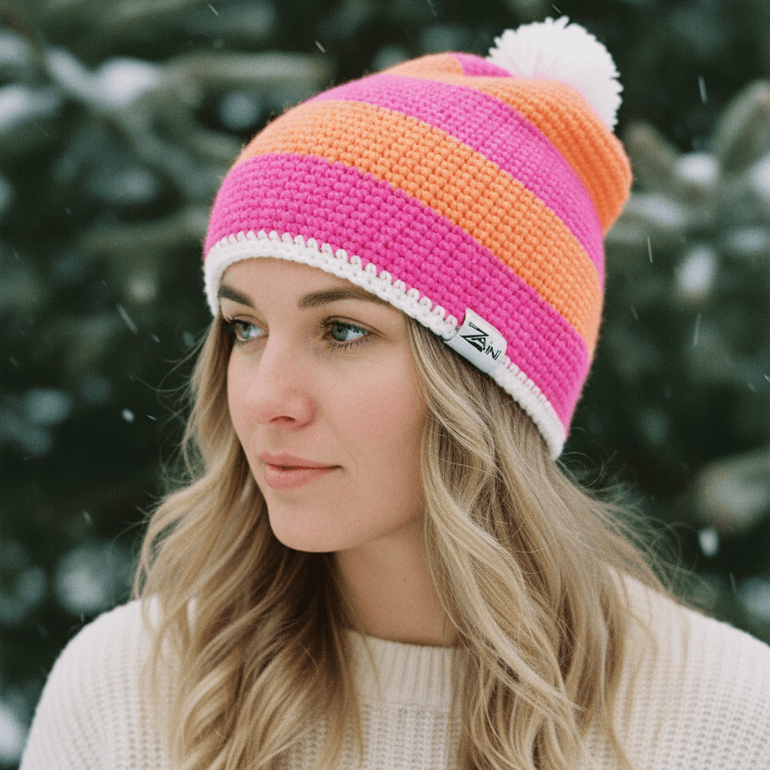 Woman wearing a colorful striped beanie with a white pom-pom against a snowy background