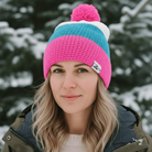 Person wearing a colorful knit beanie with a pom-pom in a snowy outdoor setting