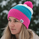 Person wearing a colorful knit beanie with a blurred snowy background