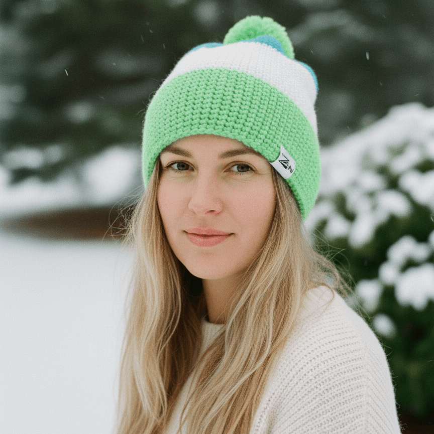 Woman wearing a green and white beanie in a snowy outdoor setting