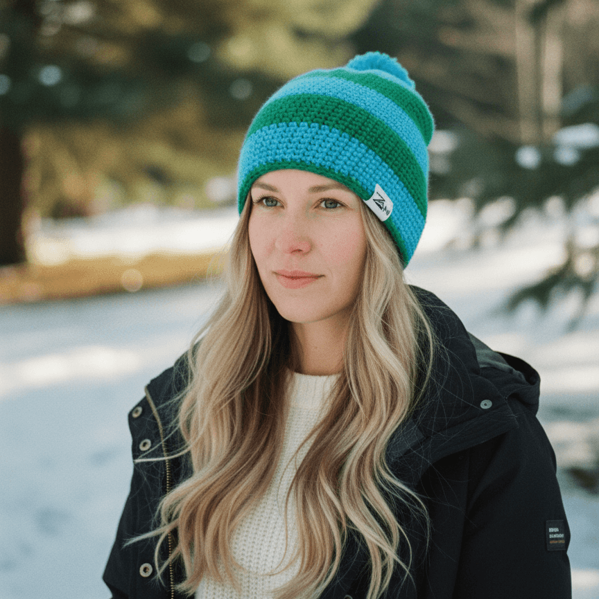Woman wearing a blue and green striped beanie in a snowy forest setting