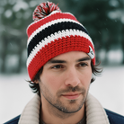 Man wearing a red, black, and white knit beanie in a snowy setting