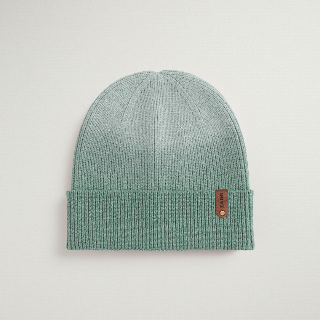 Green knit beanie with a brand tag on a light gray background