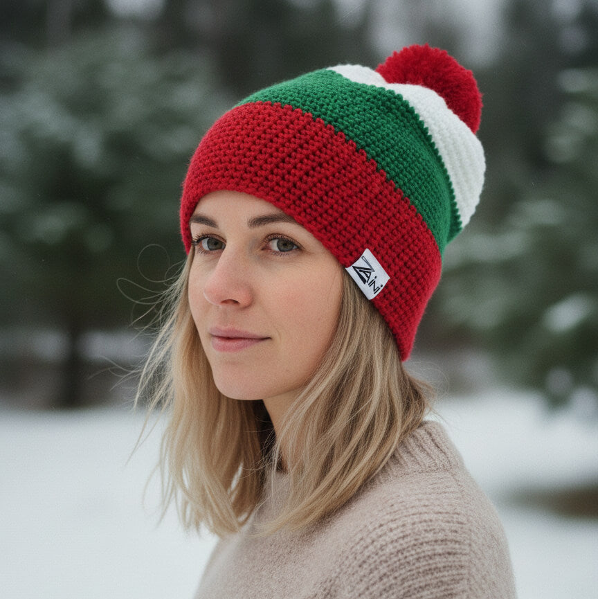 Woman wearing a red, green, and white striped knit beanie in a snowy landscape