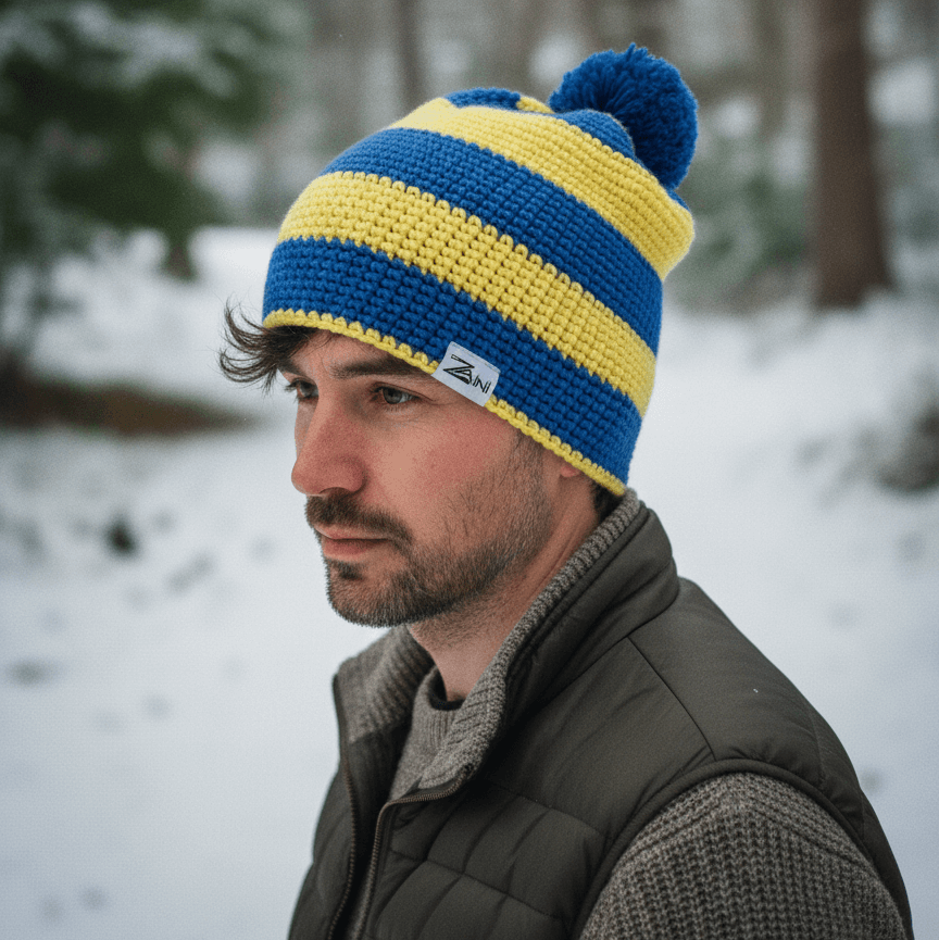 Man wearing a blue and yellow striped knit beanie in a snowy forest setting