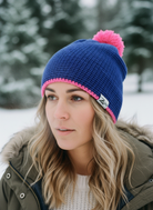 Person wearing a blue and pink beanie with a brand logo in a snowy setting