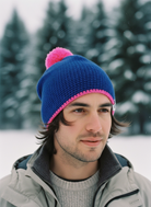 Man wearing a blue knit beanie with a pink pom-pom in a snowy landscape
