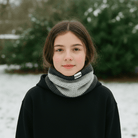 Person wearing a black hoodie and gray scarf with 'Zain' branding in a snowy outdoor setting.